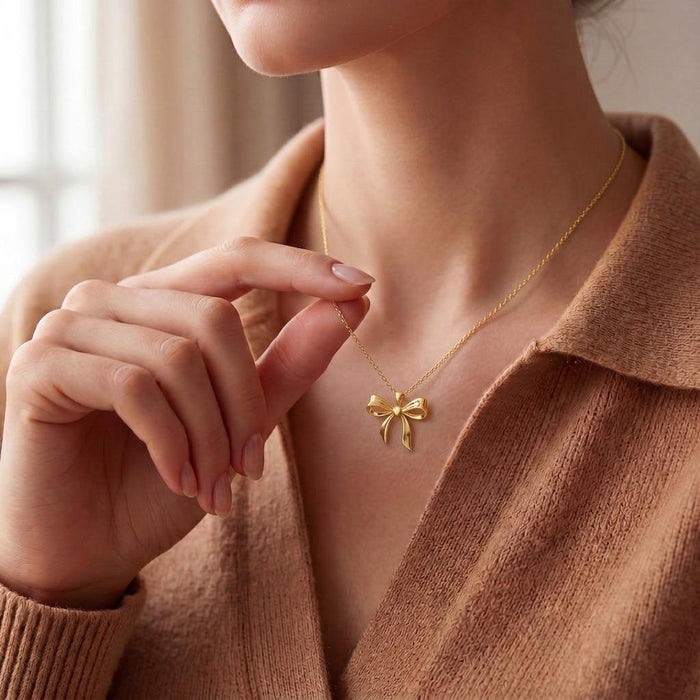 Close view of a woman holding the chain of a Gold Plated Silver Elegant Bow Pendant Necklace
