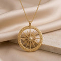 Gold-finish Elnath Star Pendant Necklace with a dimensional starburst inside a textured circular frame on folded champagne satin