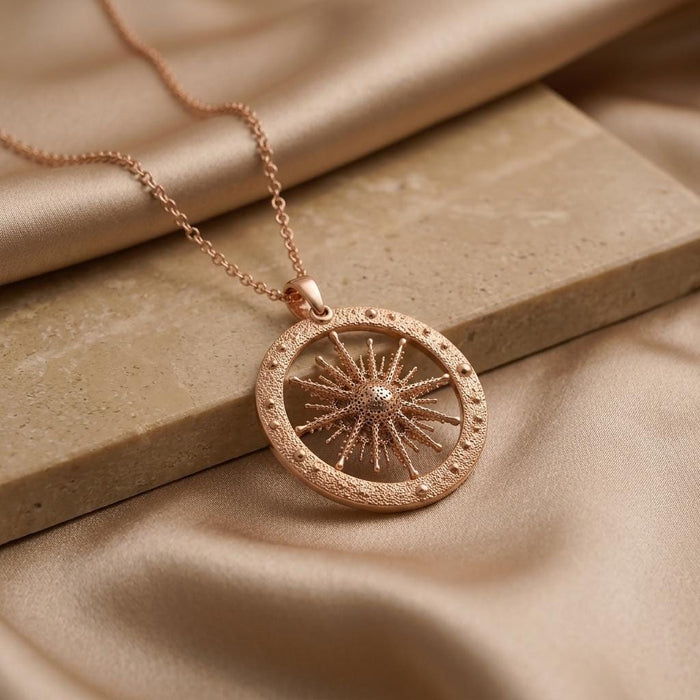Rose Gold Plated Elnath Star Pendant Necklace on champagne satin beside a stone block
