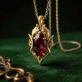 Gold Plated Silver Elven Birthstone Necklace with a dark red marquise-shaped stone on green velvet