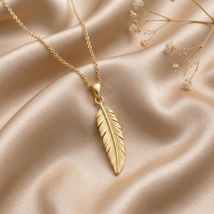 Gold Plated Silver engraved feather pendant necklace arranged on champagne satin with dried flowers