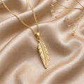 Gold Plated Silver engraved feather pendant necklace arranged on champagne satin with dried flowers