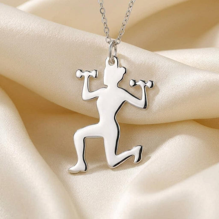 Close-up of the polished kneeling woman pendant holding two dumbbells on ivory fabric