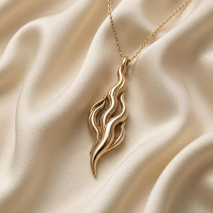 Close-up of Gold Plated Silver Flame of Venus pendant with flowing openwork lines on ivory satin
