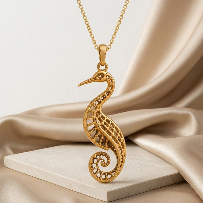 Gold Plated Silver Fossil Crane Pendant Necklace displayed above a pale stone slab with champagne satin