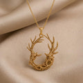 Gold Plated Silver Fossil Deer Relic pendant with paired deer profiles and branching antlers on beige satin