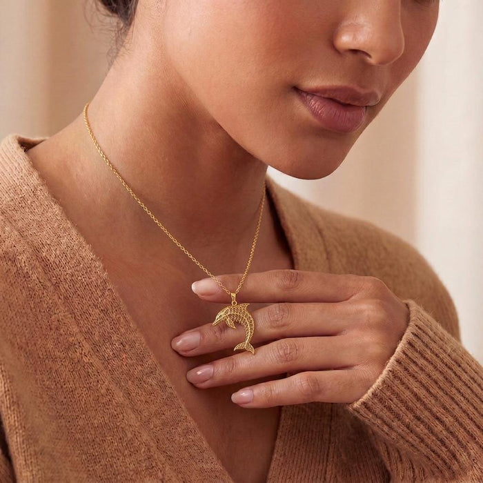 Gold Plated Silver Fossil Dolphin Artifact Necklace worn at the neckline with a neutral knit sweater