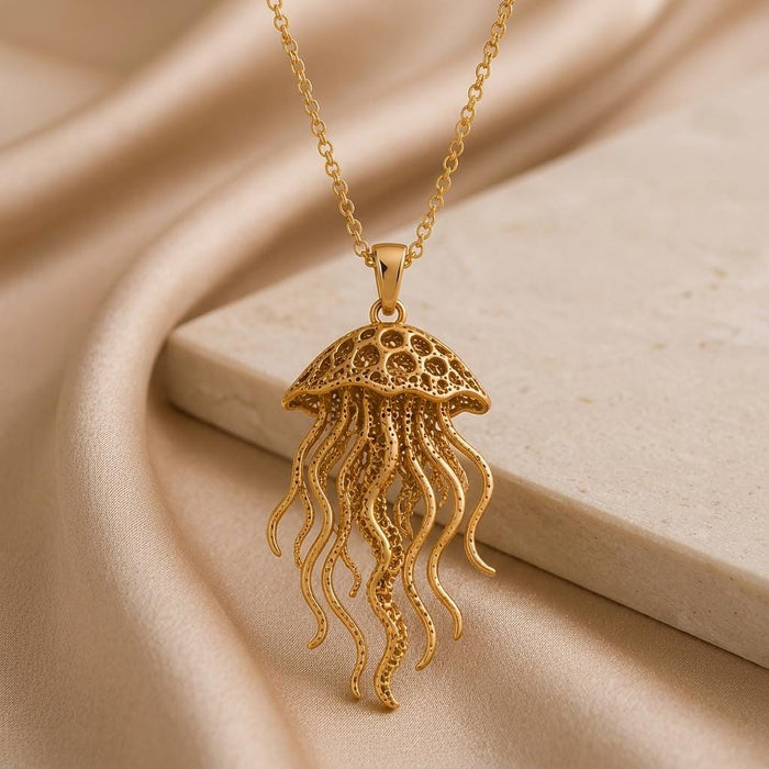 Gold Plated Silver Fossil Jellyfish Halo necklace on champagne satin beside a rectangular stone block