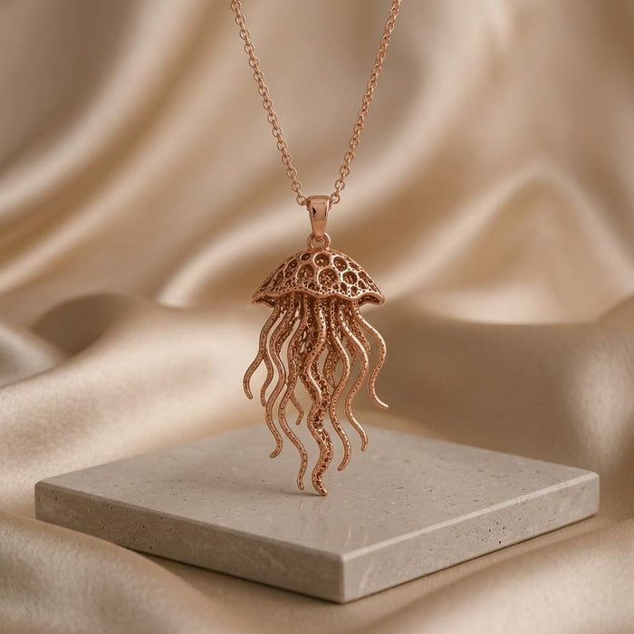 Rose Gold Plated Fossil Jellyfish Halo necklace suspended above a square stone slab on champagne satin