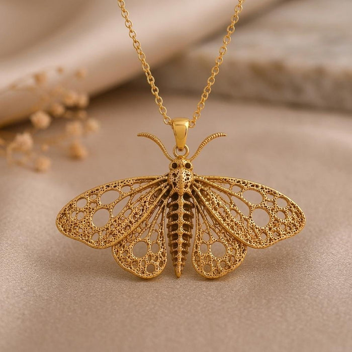 Close-up of a Gold Plated Silver fossil moth pendant with circular wing cutouts, curved antennae, and a segmented center body