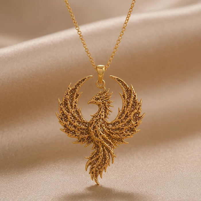 Gold Plated Silver Fossil Phoenix Crest Necklace with textured wings on beige draped fabric