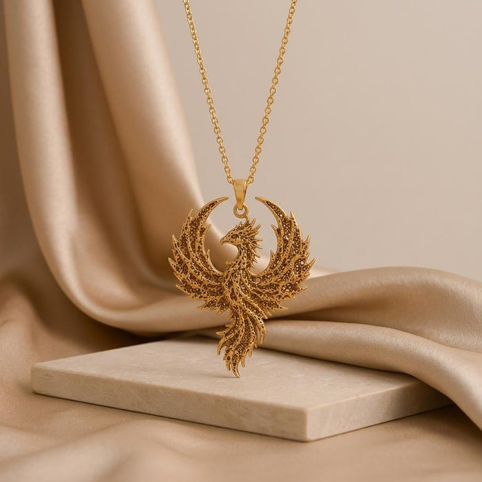 Gold Plated Silver Fossil Phoenix Crest Necklace above a pale stone block and beige draped fabric