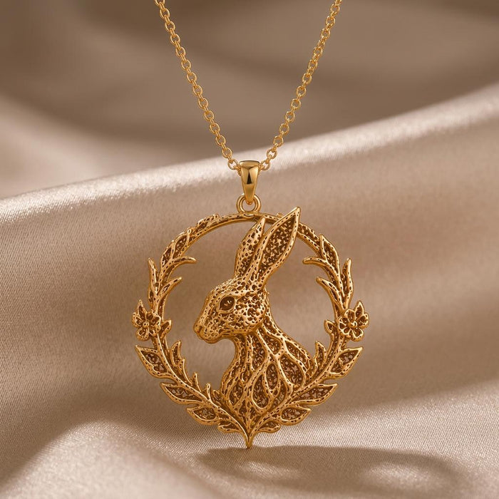 Gold Plated Silver Fossil Rabbit Halo Necklace with a textured rabbit profile inside a leafy circular halo on champagne satin