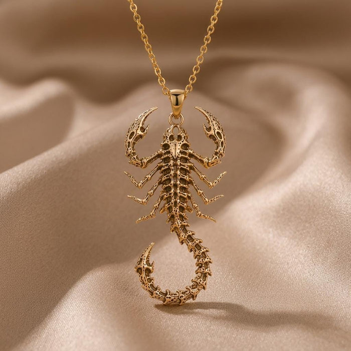 Gold Plated Silver Fossil Scorpion Spine pendant hanging above draped cream satin