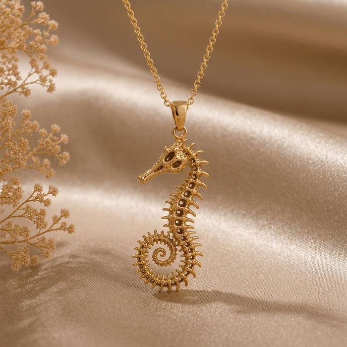 Gold Plated Silver fossil seahorse spine pendant necklace on champagne satin beside dried flowers