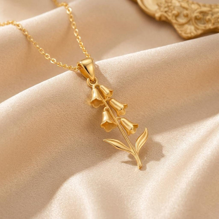 Close-up of a gold-finish foxglove pendant with bell-shaped blooms and paired leaves