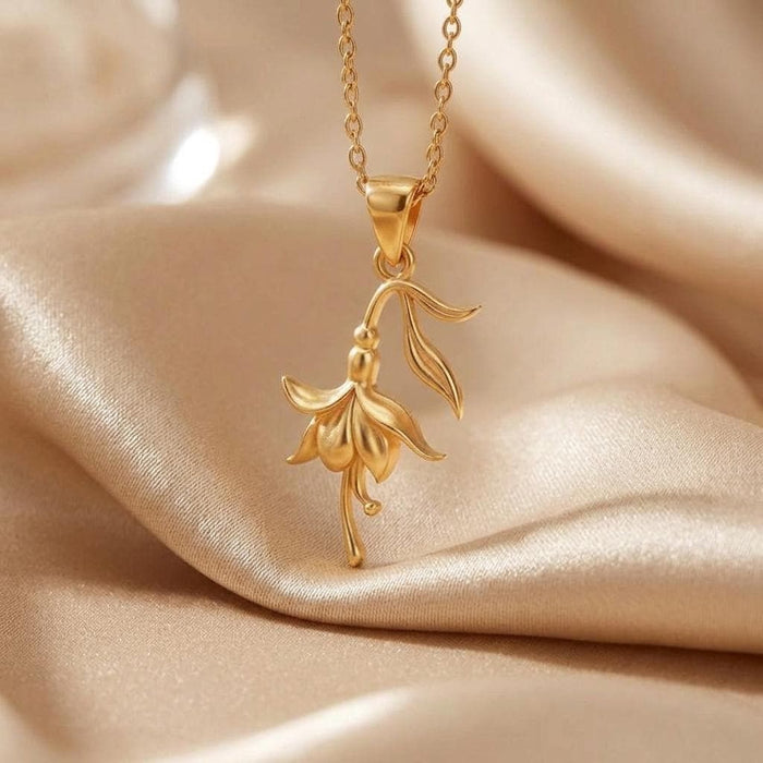 Gold Plated Silver Fuchsia Flower Necklace pendant with cascading petals displayed on satin fabric