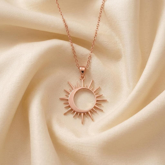 Rose-tone Solar Eclipse Necklace arranged on ivory satin