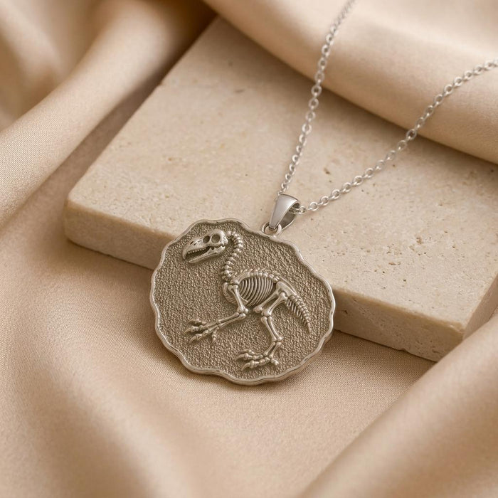 Silver Gastornis fossil medallion pendant beside a light stone display block