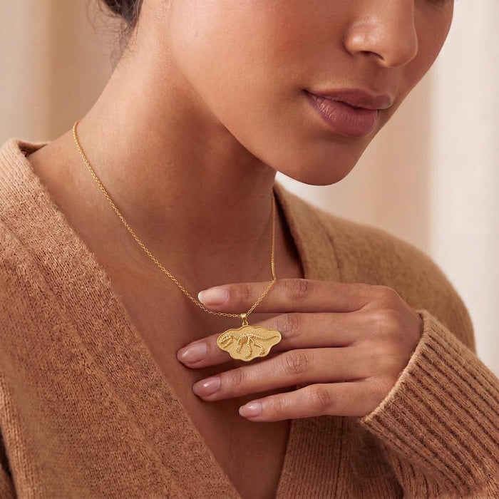 Giganotosaurus fossil pendant necklace worn at the neckline with a neutral knit top