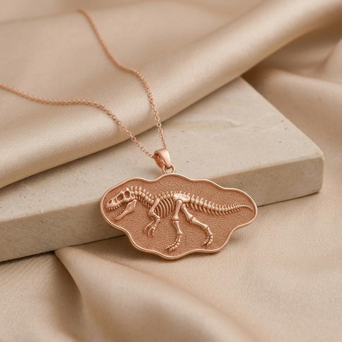 Rose Gold Plated Giganotosaurus fossil pendant necklace displayed on stone and satin