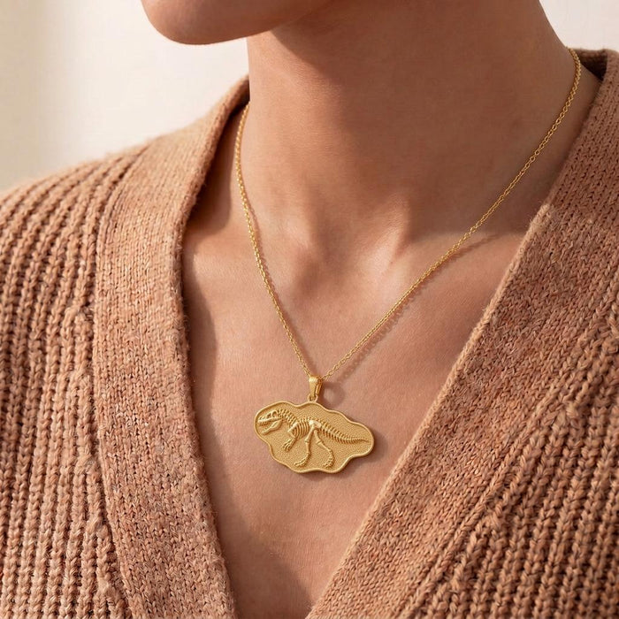 Gold-finish Giganotosaurus skeleton necklace worn with a brown knit cardigan