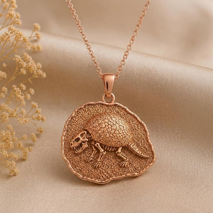 Rose Gold Plated Glyptodon fossil medallion necklace beside dried flowers