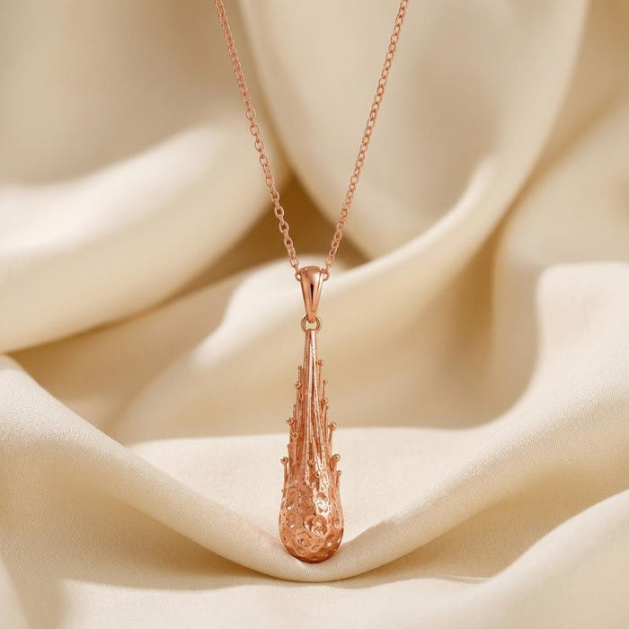 Rose-toned textured drop pendant necklace displayed on ivory satin