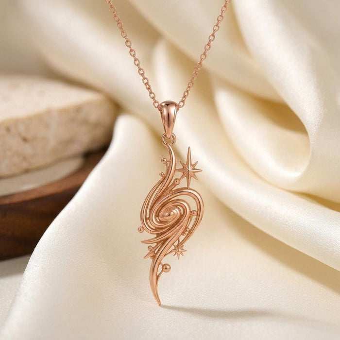 Golden Nebula Pendant Necklace in Rose Gold Plated on ivory satin, showing the elongated spiral, bead-like details, and two pointed stars
