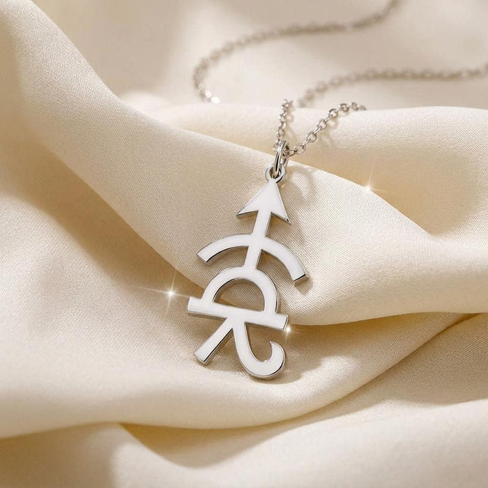 Close-up of the Achilles symbol pendant on cream satin, showing its pointed top and central arch
