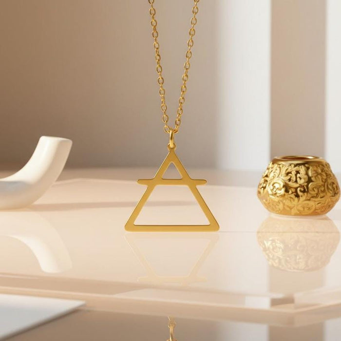 Air Element Necklace with an open triangle and horizontal bar pendant displayed on a cream reflective surface