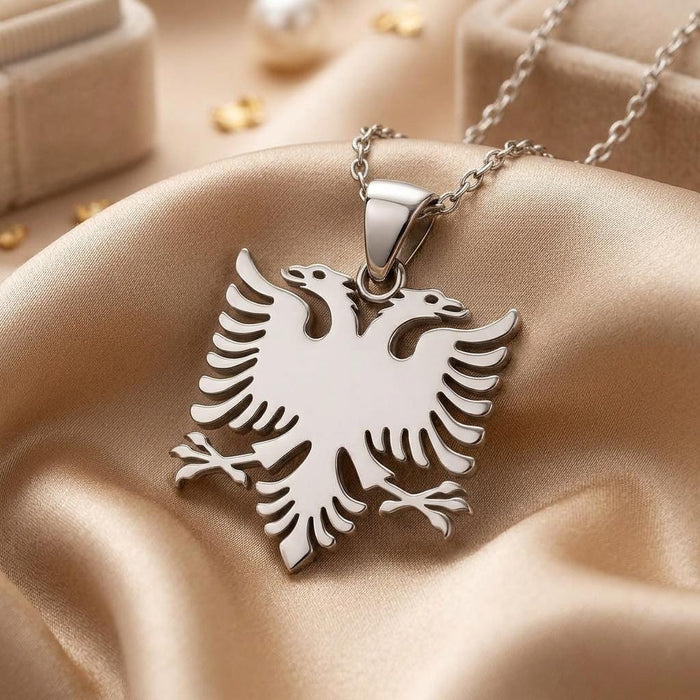 Close-up of a silver double headed Albanian eagle pendant on champagne satin