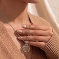 Close neckline view of the Alloces Seal pendant necklace worn with a brown knit cardigan