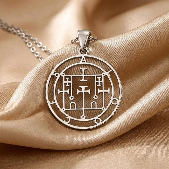 Close-up of the Alloces Seal pendant showing concentric rings and geometric linework on champagne satin