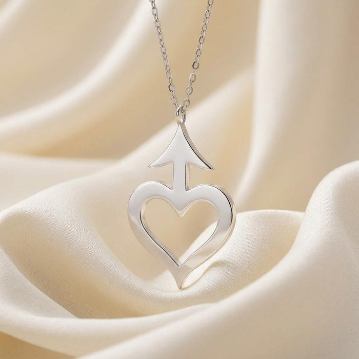 close-up of silver Amor Symbol Necklace with polished open heart and arrow pendant on ivory satin