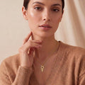 Model wearing a Gold Plated Silver Antimony Symbol Necklace with curved upper tips and a lower cross