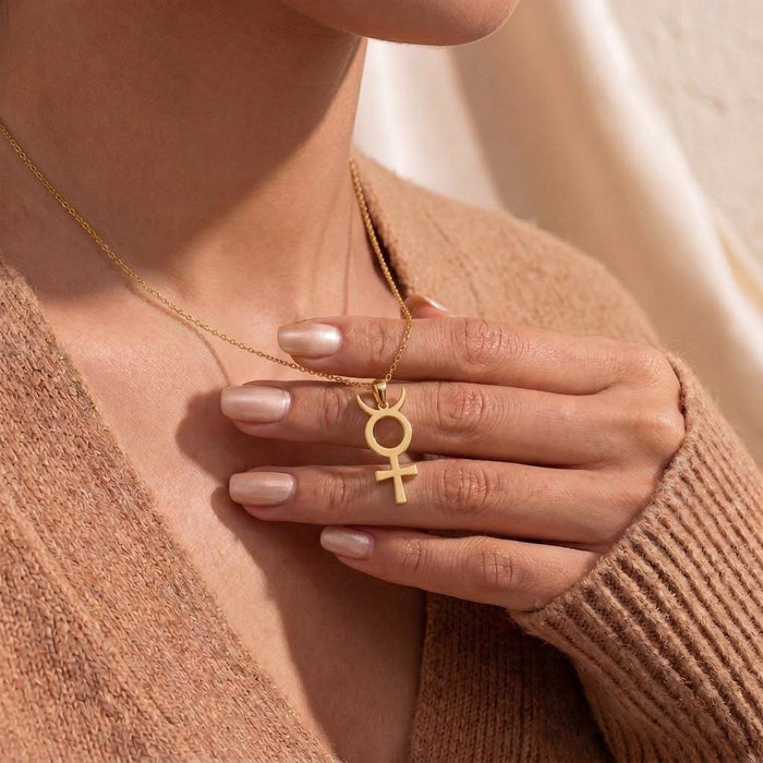 Close neckline view of a model holding a Gold Plated Silver Antimony Symbol Necklace