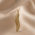 Gold Plated Silver Arthropleura pendant necklace with repeated textured segments on beige draped fabric