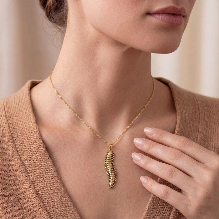 Gold Plated Silver Arthropleura pendant necklace worn at the neckline with a beige knit top