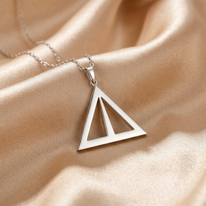 Close-up of the Asia Symbol Necklace triangular openwork pendant on champagne satin