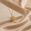 Gold Plated Silver Aspen Glow tree pendant necklace on a stone slab over champagne satin