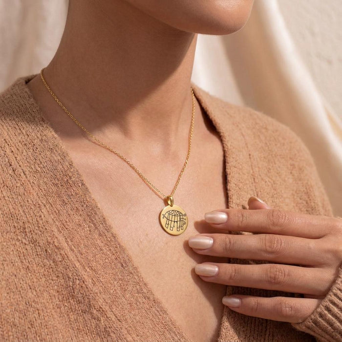 Gold-tone round Bifrons sigil pendant worn at the collarbone with a beige knit sweater