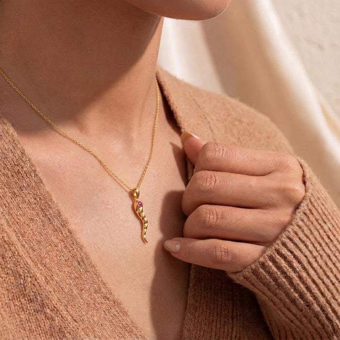 Gold Plated Silver Birthstone Horn Necklace with a pink stone accent worn with a knit V-neck cardigan