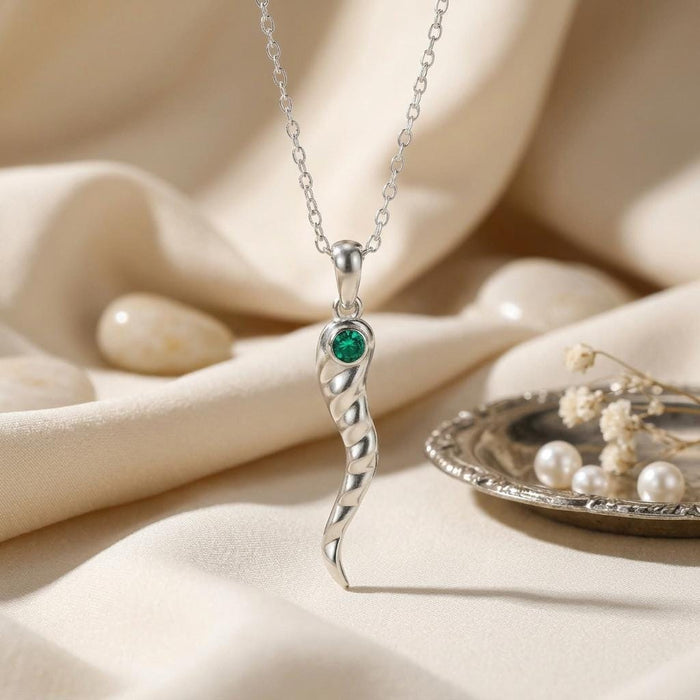 Silver Birthstone Horn Necklace with a green stone accent displayed on cream fabric