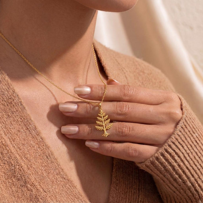 Gold Plated Silver Cedar Crest Necklace held at a model neckline over a brown knit sweater