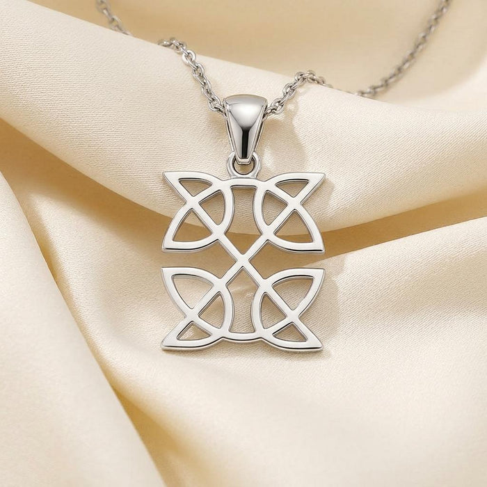 Close-up of a silver two-panel Celtic knot pendant on cream satin