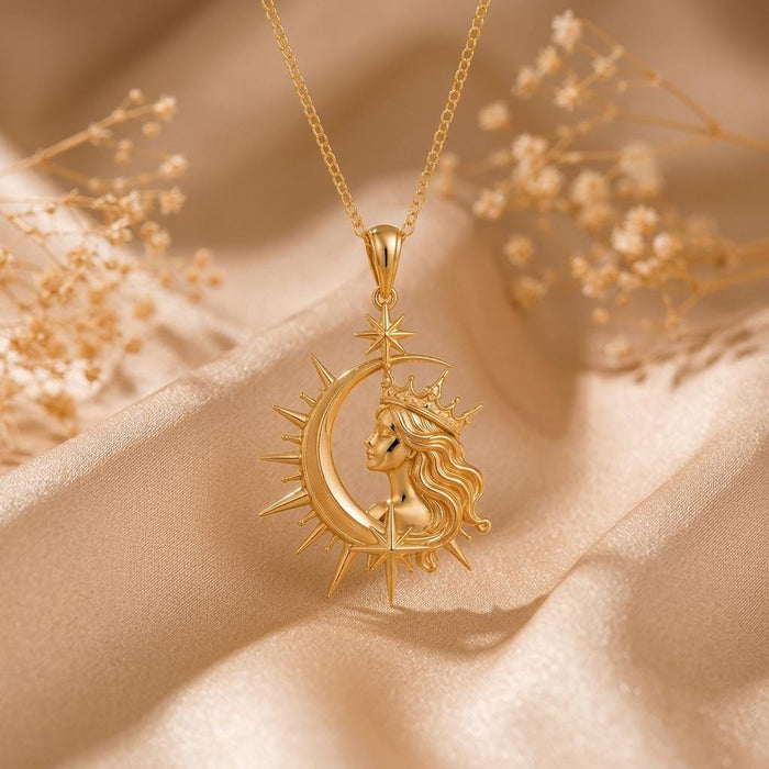 Gold Plated Silver Cosmic Queen Necklace with crowned profile and crescent frame on champagne satin beside dried floral stems