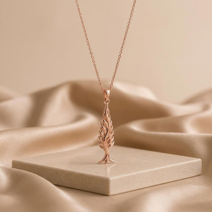 Rose Gold Plated Cypress Flame Pendant hanging above a pale stone platform and beige fabric