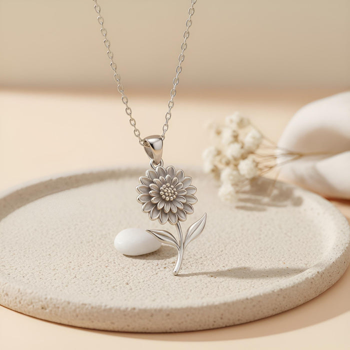 Silver Dahlia Flower Necklace with a dotted center on a textured round tray