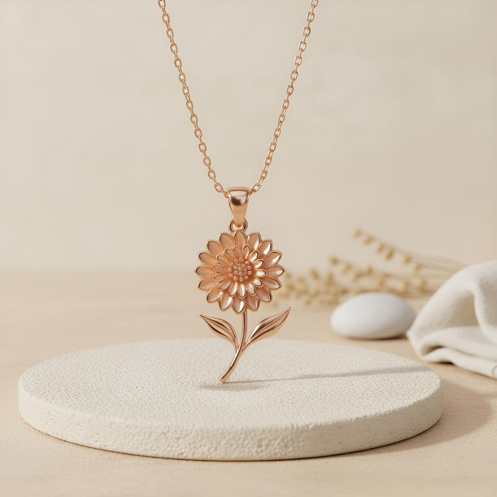 Rose Gold Plated Dahlia Flower Necklace displayed on a round pedestal with dried stems
